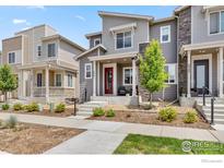 Charming townhome featuring modern architectural details, a red front door, and well-maintained landscaping at 5341 Warrior St, Frederick, CO 80504
