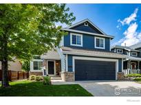 Charming two-story home features blue siding, a well-kept lawn, an attached garage, and manicured landscaping at 5609 Mount Sanitas Ave, Longmont, CO 80503