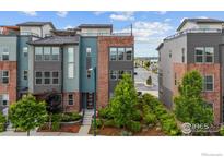 Modern townhome with mixed materials, including brick, siding, and a well maintained front yard with young trees at 9052 E 47Th Ave, Denver, CO 80238