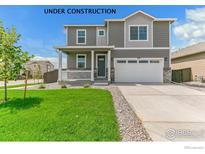 Charming two-story home featuring a covered porch, two-car garage, and well-manicured lawn at 955 Tallus St, Lochbuie, CO 80603