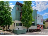 Unique modern home with colorful exterior accents and vibrant landscaping under a partly cloudy sky at 1028 Katy Ln, Longmont, CO 80504