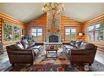 Inviting living room with vaulted ceiling, log walls, stone fireplace, and mountain views at 11997 Coal Creek Heights Dr, Golden, CO 80403