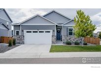 Charming single-Gathering home featuring a two-car garage, stone accents, and a well-manicured lawn at 14605 Longhorn Dr, Mead, CO 80542