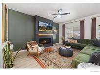 Cozy living room with fireplace, ceiling fan, green sectional sofa, and beautiful area rug at 2483 Tabor St, Berthoud, CO 80513