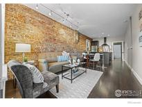 Inviting living room features exposed brick wall, modern track lighting, and neutral-toned furnishings at 3321 Navajo St, Denver, CO 80211