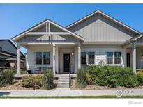 Charming home with a covered porch, landscaped front yard, and neutral-colored siding at 871 Colorado River Ave, Brighton, CO 80601