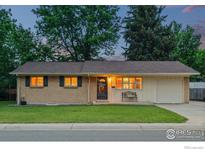 Charming single-story home features brick accents, a well-manicured lawn, and mature trees, creating a welcoming curb appeal at 10844 W 68Th Ave, Arvada, CO 80004
