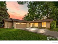 Charming single-story home with a well-manicured lawn, mature trees, and an attached garage at 11198 W 59Th Pl, Arvada, CO 80004