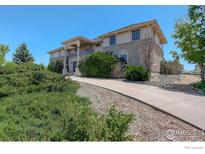 Attractive exterior of home with stone accents, mature landscaping, and a curved driveway at 14448 Hanover St, Brighton, CO 80602