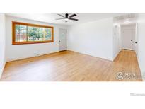 Bright living room features hardwood floors, a ceiling fan and natural light from the large window at 235 N 12Th Ave, Brighton, CO 80601