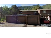 Two-story exterior showcasing attached garages and views of the lush, forested mountainside at 2919 Riverside Dr, Idaho Springs, CO 80452