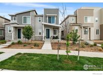 Modern townhome with gray siding, stone accents, manicured lawn, and inviting curb appeal at 5325 Spalding Pl, Frederick, CO 80504