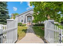 Inviting home exterior with a white picket fence, lush lawn, and gray siding at 5753 Secrest Ct, Golden, CO 80403