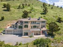 Stunning multi-level home featuring a large deck, ample parking, and an adjacent lush green hillside at 606 Sugarloaf Mountain Rd, Boulder, CO 80302