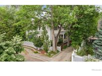 Charming two-story home featuring mature trees, a white picket fence, and a welcoming front yard at 877 Racquet Ln, Boulder, CO 80303