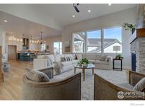 Bright, open living room with large windows, comfortable seating, fireplace, and seamless flow to the kitchen at 1030 Turnberry Cir, Louisville, CO 80027