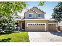 Inviting two-story home featuring a three-car garage, well-kept lawn, and mature trees at 11486 E 119Th Pl, Henderson, CO 80640