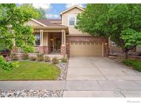 Charming home featuring a brick facade, inviting porch, well-manicured lawn, and a two-car garage at 13266 Teller Lake Way, Broomfield, CO 80020