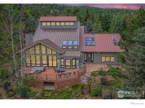 Stunning home boasts a metal roof, large deck, and walls of windows showcasing the forested surroundings at 148 Granite Dr, Boulder, CO 80302