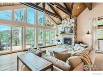 Bright living room features large windows, wood beams, fireplace, and access to a private balcony with views at 148 Granite Dr, Boulder, CO 80302
