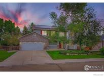 Charming two-story home with stone accents, solar panels, manicured lawn, and mature trees at 1616 Cedarwood Dr, Longmont, CO 80504