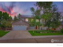 Charming two-story home with a stone facade and a well-manicured front yard at 1616 Cedarwood Dr, Longmont, CO 80504