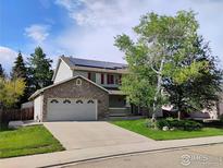 Charming two-story home with stone accents, solar panels, mature trees, and a well-manicured lawn at 1616 Cedarwood Dr, Longmont, CO 80504