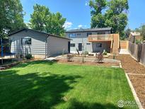 A lush backyard features a well-maintained lawn, modern patio furniture, and a grey detached garage at 1843 Spruce Ave, Longmont, CO 80501