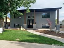Charming grey brick home featuring a manicured lawn and a welcoming walkway to the front door at 1843 Spruce Ave, Longmont, CO 80501