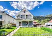 Charming two-story home with a well-manicured lawn, a welcoming porch, and a second-story balcony at 1906 Miner St, Idaho Springs, CO 80452
