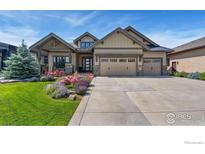 Charming exterior view of home featuring a three car garage and beautiful landscaping at 2737 Heron Lakes Pkwy, Berthoud, CO 80513