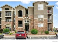 Apartment building exterior featuring stone accents, balconies, and well-maintained landscaping and parking at 3045 Blue Sky Cir # 105, Erie, CO 80516
