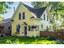 Charming yellow two-story home with lush green lawn and mature trees at 310 Judson St, Longmont, CO 80501