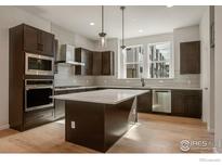 Modern kitchen featuring an island, stainless steel appliances, and dark wood cabinetry at 362 Promenade Dr, Superior, CO 80027