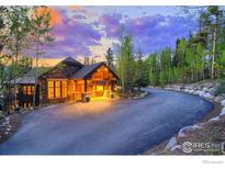 Beautiful stone house with a covered porch and well-lit windows on a paved drive with lush landscaping at 41 Stillson Placer Ter, Breckenridge, CO 80424