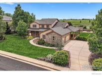 Beautiful tan two-story home with stone accents, mature landscaping, and an attached two car garage at 6544 Saddleback Ave, Longmont, CO 80504