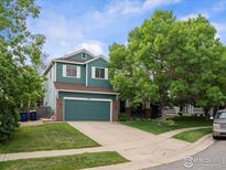 Charming two-story home featuring an attached garage, well-maintained lawn and mature trees providing shade at 707 Starkey Ct, Erie, CO 80516