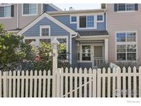 Charming two-story blue home with a white picket fence and well-manicured landscaping at 729 Snowberry St, Longmont, CO 80503