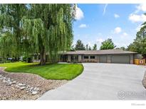 Inviting single-story home featuring a well-manicured lawn, mature trees, and a long driveway leading to an attached garage at 7720 Ferris Way, Boulder, CO 80303