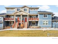 Inviting townhome featuring light blue siding, a red door, and charming balconies at 883 Widgeon Cir, Longmont, CO 80503