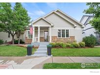 Charming home featuring stone accents, well-manicured lawn, and a welcoming front porch with an American flag at 1518 Hollyberry St, Berthoud, CO 80513