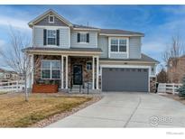 Two-story home featuring stone accents, a covered porch, and an attached two-car garage with an extended driveway at 1682 Dorothy Cir, Longmont, CO 80503
