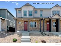 Charming townhome featuring a stone facade, gray siding, and a welcoming red front door at 18724 E 99Th Ave, Commerce City, CO 80022