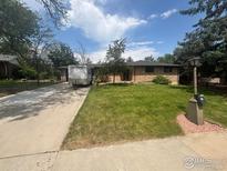 Charming ranch-style home featuring a well-maintained lawn, long driveway and mature trees at 28 University Dr, Longmont, CO 80503