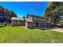 Charming two-story home boasts a well-manicured lawn and inviting red door at 5004 Fox Hill Dr, Longmont, CO 80504