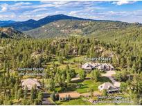 Panoramic aerial view of the estate with multiple buildings nestled in a lush mountain setting at 6917 Timbers Dr, Evergreen, CO 80439