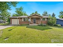 Charming brick home featuring a well-manicured lawn, covered porch with seating, and attached garage at 7423 Saulsbury St, Arvada, CO 80003