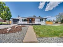 Charming single story home with wood accents, a well-manicured lawn, and a black garage at 7826 Joan Dr, Denver, CO 80221