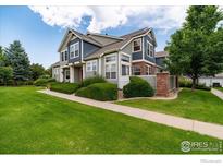 Charming townhouse featuring manicured lawn, beautiful landscaping, and inviting architectural details at 13900 Lake Song Ln # 3, Broomfield, CO 80023