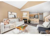 Cozy living room with modern furniture, fireplace, and seamless flow into the kitchen area at 14246 Pikeminnow Pl, Broomfield, CO 80023